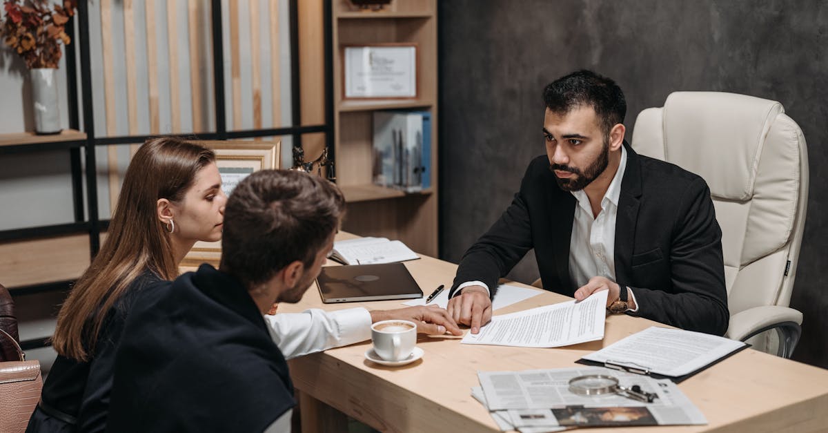 Lawyer discussing legal documents with clients at office desk.