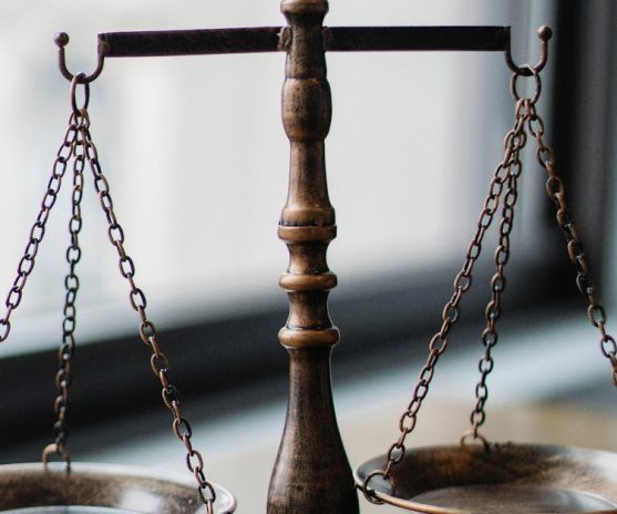 ميزان العدالة والمطرقة القانونية على مكتب مضاء بالضوء الطبيعي، يرمز إلى أهمية الاستعانة بمحامٍ في أولاد تايمة لضمان الدفاع عن الحقوق القانونية.